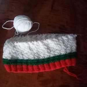 Peut inclure: Un bonnet tricot&eacute; blanc, vert et rouge avec une pelote de laine blanche.