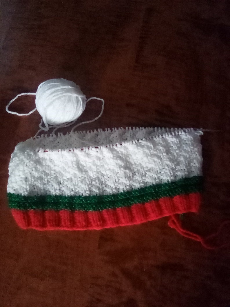 Peut inclure: Un bonnet tricot&eacute; blanc, vert et rouge avec une pelote de laine blanche.