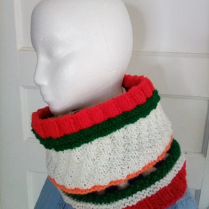 Peut inclure: Un tour de cou en tricot ray&eacute; blanc, rouge, vert et orange. Le tour de cou est fait de fil doux et est parfait pour se tenir au chaud en hiver.