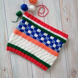 May include: A knitted scarf with a white background and stripes of red, orange, green, and blue. The scarf has a checkered pattern in blue and white.