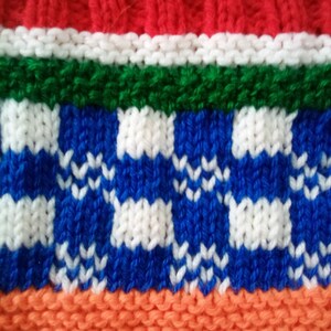 Peut inclure: Gros plan sur un tissu tricot&eacute; avec un motif ray&eacute; color&eacute;. Le tissu est rouge, blanc, vert, bleu, orange et blanc. Les rayures bleues et blanches ont un motif &agrave; carreaux.