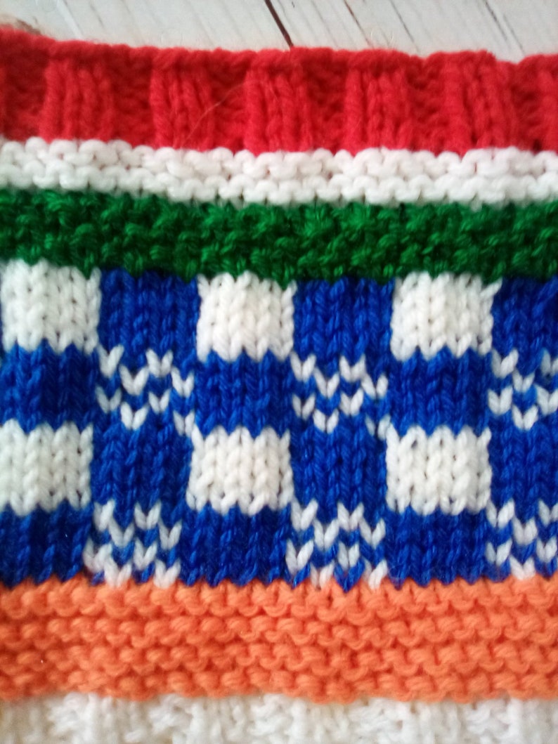 Peut inclure: Gros plan sur un tissu tricot&eacute; avec un motif ray&eacute; color&eacute;. Le tissu est rouge, blanc, vert, bleu, orange et blanc. Les rayures bleues et blanches ont un motif &agrave; carreaux.