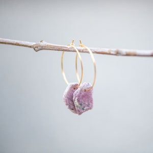 Peut inclure: Une paire de boucles d'oreilles cr&eacute;oles dor&eacute;es avec des accents de pierres pr&eacute;cieuses roses et blanches suspendues &agrave; une branche.