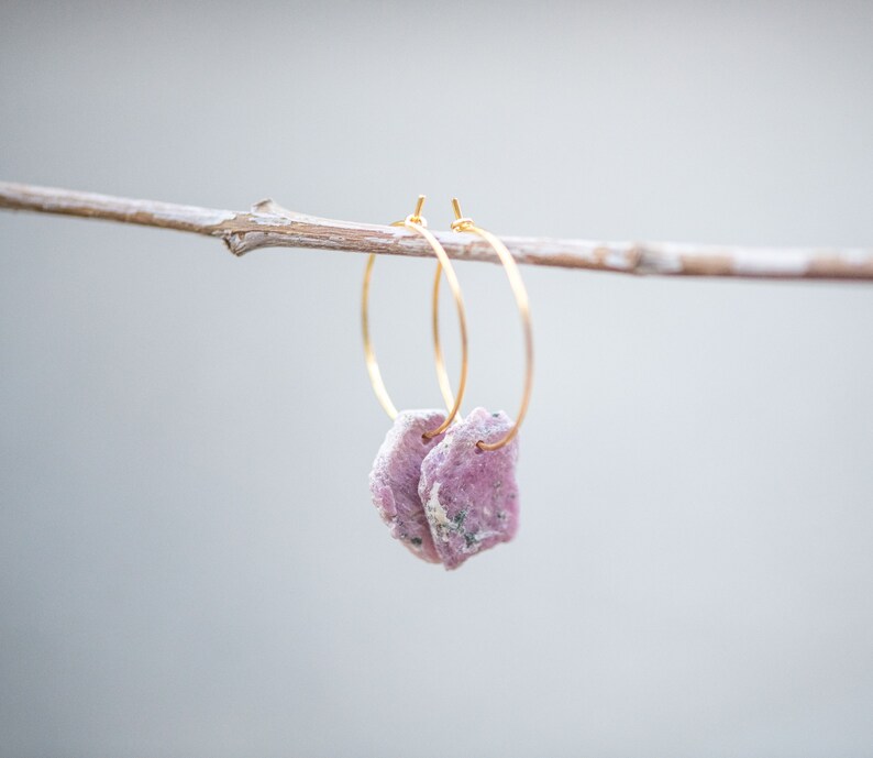 Peut inclure: Une paire de boucles d'oreilles cr&eacute;oles dor&eacute;es avec des accents de pierres pr&eacute;cieuses roses et blanches suspendues &agrave; une branche.