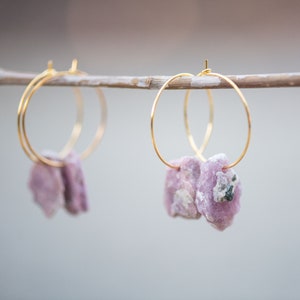 Peut inclure: Une paire de boucles d'oreilles cr&eacute;oles dor&eacute;es avec des accents de pierres pr&eacute;cieuses roses et blanches suspendues &agrave; une branche.