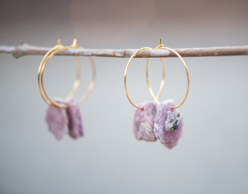 Peut inclure: Une paire de boucles d'oreilles cr&eacute;oles dor&eacute;es avec des accents de pierres pr&eacute;cieuses roses et blanches suspendues &agrave; une branche.