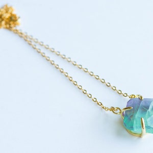 May include: A gold chain necklace with a large, faceted, green and purple fluorite pendant.