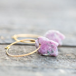 Peut inclure: Boucles d'oreilles cr&eacute;oles en or avec des accents de pierres pr&eacute;cieuses brutes roses et blanches.