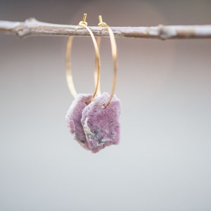 Peut inclure: Boucles d'oreilles cr&eacute;oles en or avec un pendentif en pierre rose et grise.