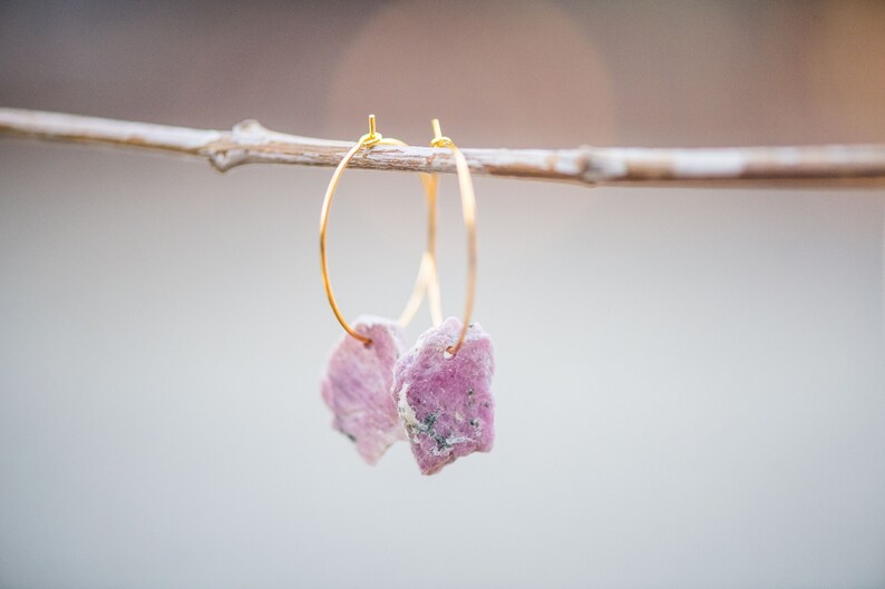 Peut inclure: Une paire de boucles d'oreilles cr&eacute;oles en or avec des accents de pierres pr&eacute;cieuses roses et blanches. Les boucles d'oreilles sont suspendues &agrave; une branche.