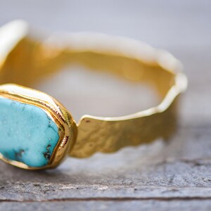 May include: A gold ring with a turquoise gemstone set in a textured band.