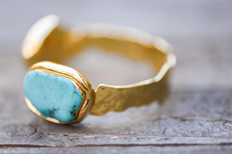 May include: A gold ring with a turquoise gemstone set in a textured band.