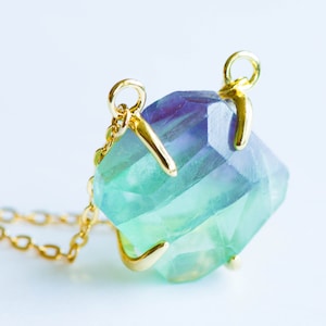 Puede incluir: Un collar de oro con un gran colgante de fluorita facetado. La fluorita es de un color verde y azul vibrante.