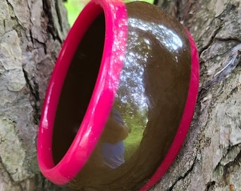 May include: A brown and pink resin bangle bracelet. The bracelet is wide and has a glossy finish.