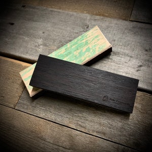 May include: Two rectangular wooden blocks, one black and one with a green and white marbled pattern. The black block has the text "Fehr Frameworks" engraved on it.