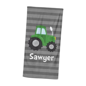 May include: A gray and white striped beach towel with a green tractor illustration and the name "Sawyer" printed in white.