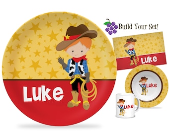 May include: A personalized children's dinnerware set featuring a cartoon cowboy with a red bandana and a lasso. The set includes a yellow and red plate, a yellow bowl, and a white mug. The name "Luke" is printed on each piece.