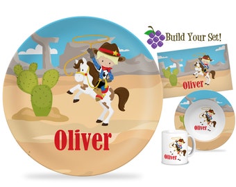 May include: A personalized children's dinnerware set featuring a cartoon cowboy riding a horse in a desert landscape. The set includes a plate, bowl, and mug, all with the name "Oliver" printed on them. The set is perfect for a child who loves cowboys and horses.