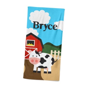 May include: A red barn with a white cow in front of it. The sky is blue with a white cloud. The text "Bryce" is written on the towel.