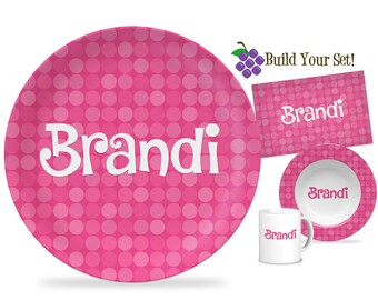 May include: Pink polka dot dinnerware set with the name "Brandi" on each piece. The set includes a large plate, a small bowl, and a mug.