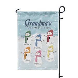 May include: A blue garden flag with the text "Grandma's Snow Buddies" and six snowmen with different colored hats and scarves. The snowmen are labeled with the names William, Martha, Lincoln, Bobby, Marisca, and Martin.