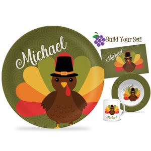 May include: A personalized Thanksgiving dinnerware set featuring a cartoon turkey wearing a pilgrim hat. The set includes a plate, bowl, and mug, all with the name "Michael" printed on them. The background is a green swirl pattern.