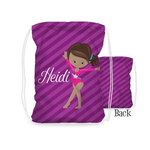May include: Purple drawstring bag with a diagonal stripe pattern. The bag features a cartoon illustration of a gymnast with brown skin, wearing a pink leotard with a star. The name "Heidi" is written in white cursive on the bag. The back of the bag is shown with the word "Back" printed on it.