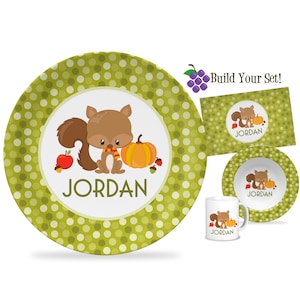 May include: A green and white polka dot dinner plate with a cartoon squirrel holding an acorn and a pumpkin. The plate says "JORDAN" in a white font.