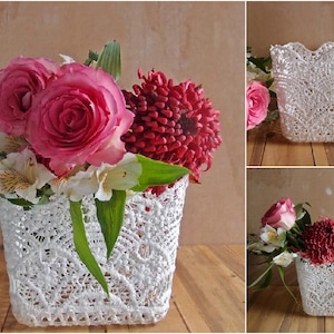 May include: A white lace flower vase with a bouquet of pink roses, white flowers, and red flowers.