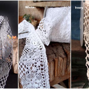 May include: Three spools of delicate crochet lace trim in gray, white, and ivory. The lace is a delicate, openwork design with a floral pattern.