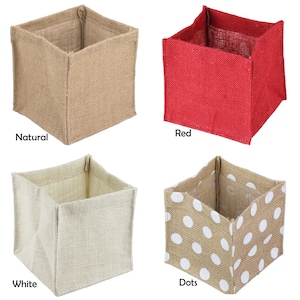 May include: Four square jute storage boxes in different colors and patterns. The boxes are natural, red, white, and white with brown polka dots.