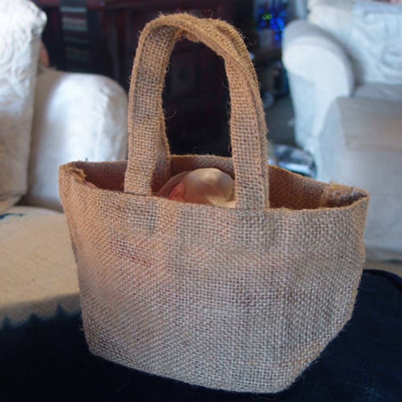 Pu&ograve; includere: Una borsa tote in juta marrone con una trama naturale tessuta. La borsa ha due spesse cinghie ed &egrave; vuota.