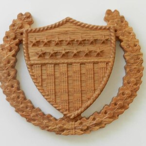 May include: A wooden shield with a carved design of stars and stripes, surrounded by a wreath of leaves.