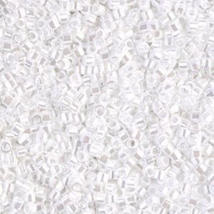 May include: A close-up view of a pile of small, white, rectangular beads. The beads have a slightly iridescent quality, reflecting light. The beads are scattered, creating a textured surface. These beads are suitable for jewelry making and crafts.