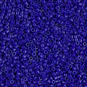 May include: Close-up of a pile of small, cylindrical, dark blue glass beads. The beads are uniform in size and shape, with a hole running through the center. The beads are scattered, creating a textured surface. Ideal for jewelry making and crafts.
