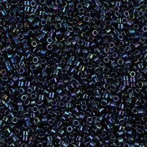 May include: A close-up shot of a pile of small, cylindrical beads. The beads are primarily dark blue with iridescent color shifts of purple, green, and gold. The beads are uniform in size and shape, with a hole running through the center.
