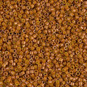 May include: A close-up shot of numerous small, cylindrical beads. The beads are a warm, earthy brown color with a yellow-green interior. They are densely packed together, creating a textured surface. These beads are likely used for jewelry making or other craft projects.