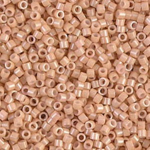 May include: A close-up view of a pile of small, cylindrical beads in a light peach color. Each bead has a hole running through the center. The beads are scattered, creating a textured surface. These beads are suitable for jewelry making and crafts.