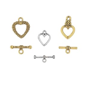 May include: Assortment of gold and silver heart-shaped toggle clasps for jewelry making. The clasps feature different designs, including a beaded heart, a simple heart, and a heart with a decorative flourish.