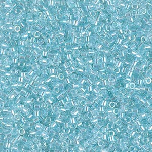 May include: A close-up view of a pile of small, light blue seed beads. The beads are cylindrical with a hole running through the center. The beads have a slightly iridescent quality, reflecting light. These beads are ideal for jewelry making and crafts.
