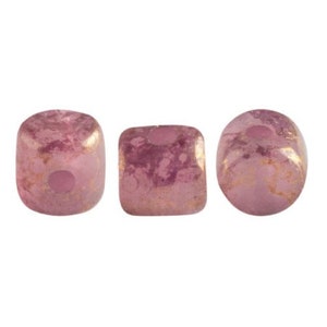 May include: Three pink glass beads with gold flecks. The beads are square shaped with rounded edges.
