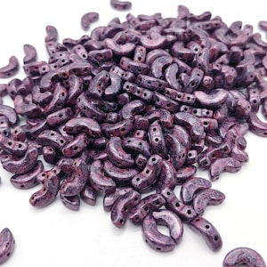 May include: A large pile of purple and red half-round ceramic beads with holes for stringing.