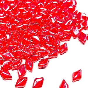 May include: A pile of red glass beads in a diamond shape. The beads are shiny and have a slight iridescent quality.