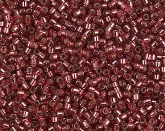 May include: Close-up of a pile of small, cylindrical beads in a metallic rose color. The beads are densely packed, creating a textured surface. The beads are likely used for jewelry making or other craft projects.