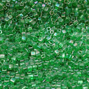May include: A large collection of small, square-shaped glass beads in a vibrant, translucent emerald green color. Each bead features a central hole and a smooth, reflective surface with subtle iridescent highlights that catch the light.