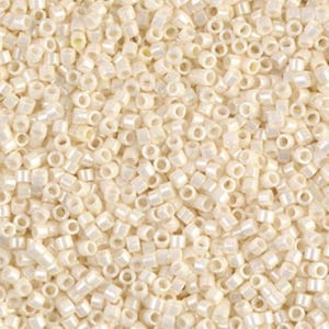 May include: Close-up of a pile of small, off-white seed beads. The beads are cylindrical with a hole running through the center, and they have a slightly iridescent finish. The beads are scattered, creating a textured surface.