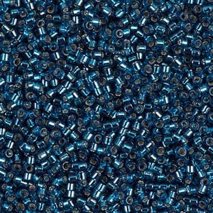 May include: A close-up shot of a pile of small, cylindrical beads. The beads are a deep teal color with a metallic sheen, reflecting light. The beads are scattered, creating a textured surface. These beads are ideal for jewelry making and crafts.
