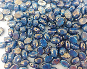 May include: A large group of blue and gold oval-shaped glass beads. The beads have a speckled, iridescent finish.