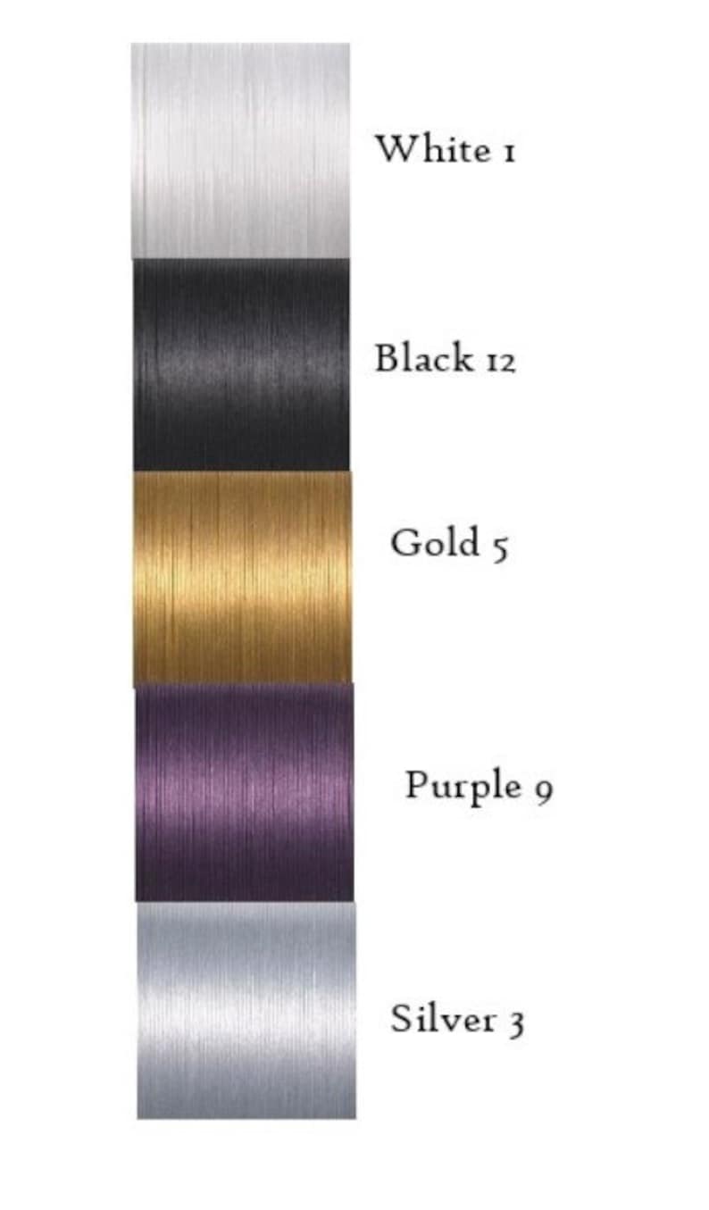 May include: Five spools of thread in different colors: white, black, gold, purple, and silver. Each spool has a number next to its color: 1, 12, 5, 9, and 3.