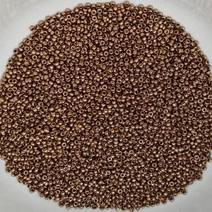 May include: A large quantity of small, round, copper-colored beads. The beads are arranged in a close-up view, filling the entire frame.